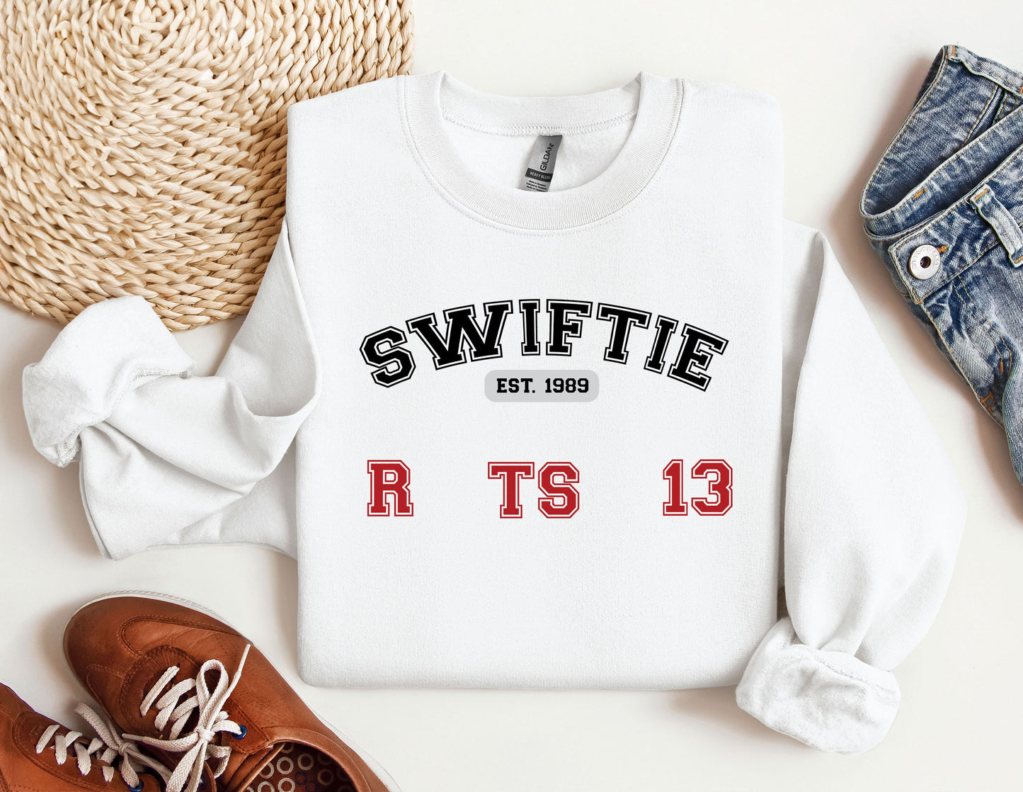 a white sweater with the words swiffie on it next to a pair of