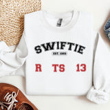 a white sweater with the words swiffie on it next to a pair of