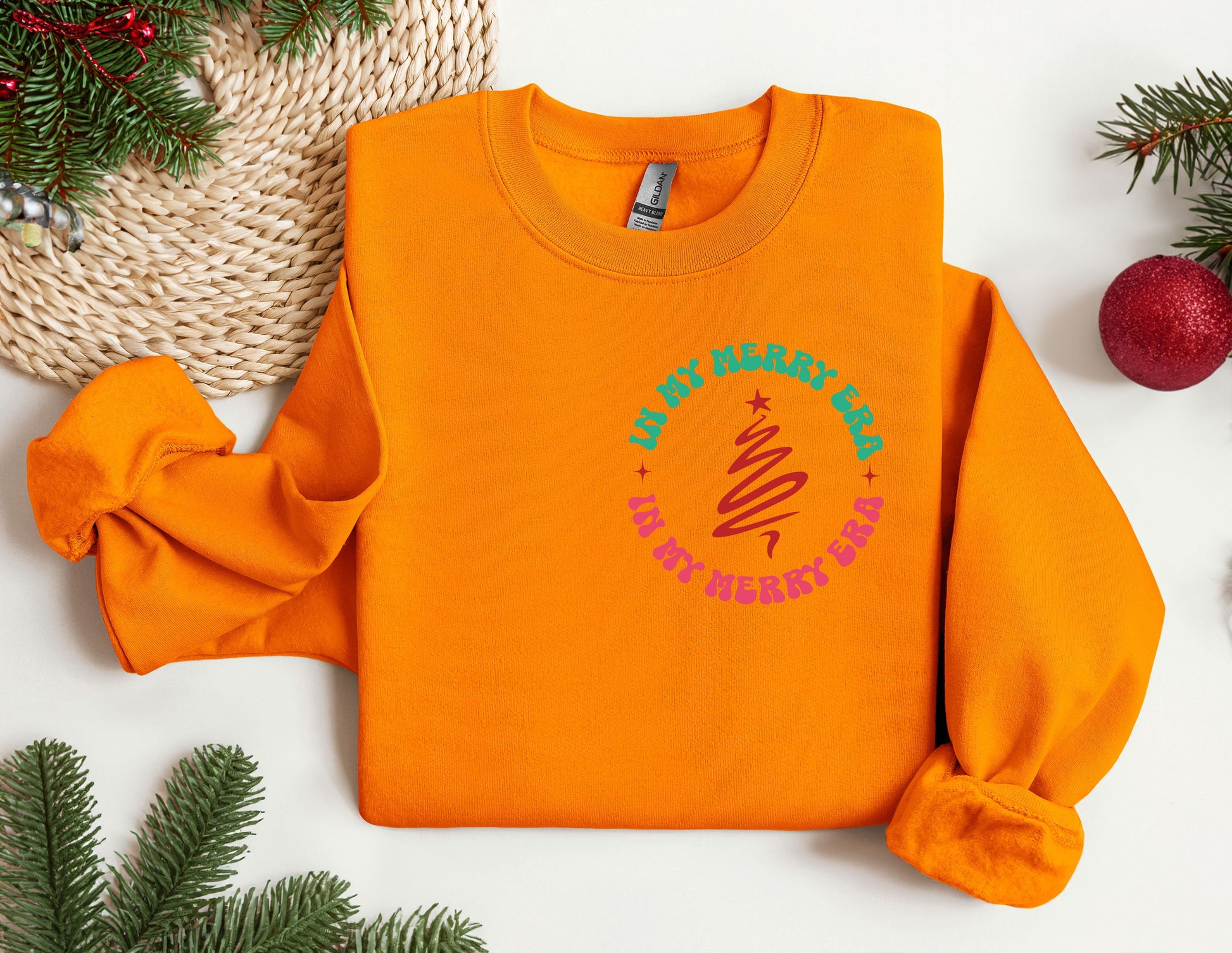 an orange sweatshirt with a green and pink design on it