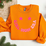 an orange sweatshirt with a pink mom on it
