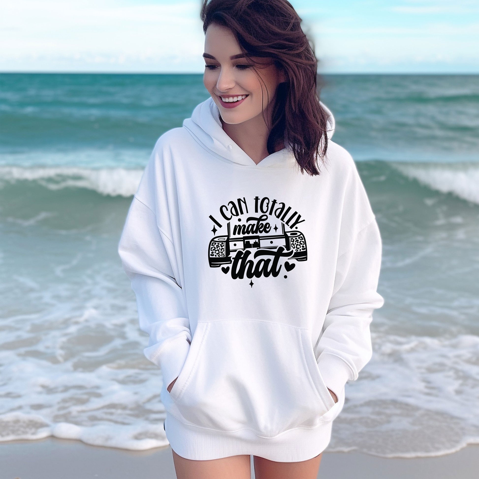 a woman standing on a beach wearing a white hoodie