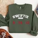 a sweater with the words swiffie on it next to a pair of shoes