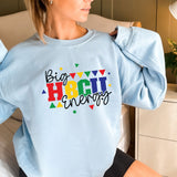 a woman sitting on a bed wearing a blue sweatshirt