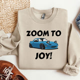 a sweater that says zoom to joy with a blue car on it