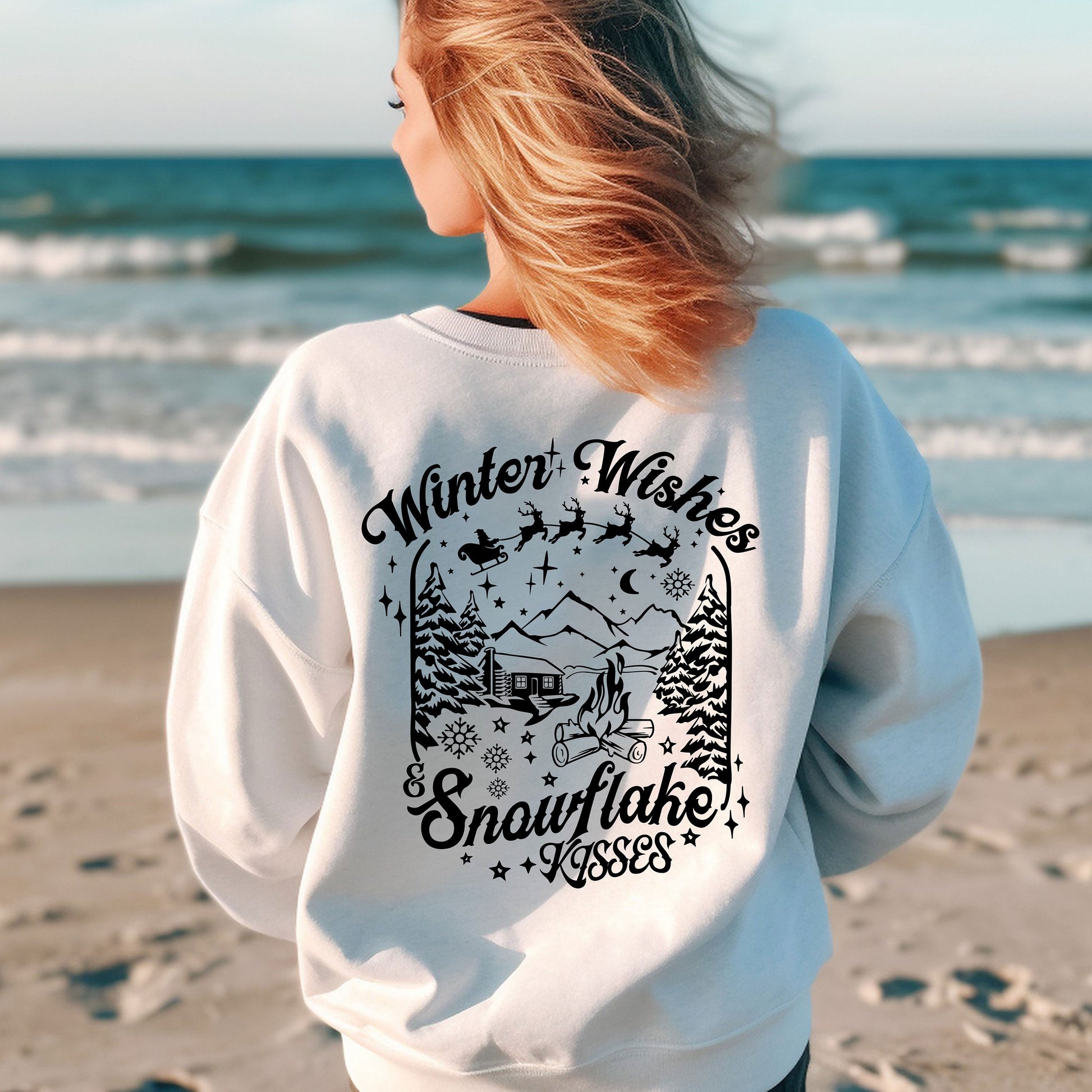 a woman standing on a beach wearing a white sweatshirt