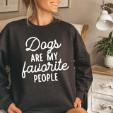 a woman sitting on a bed wearing a sweatshirt that says dogs are my favorite people