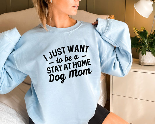 a woman sitting on a bed wearing a blue sweatshirt