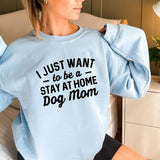 a woman sitting on a bed wearing a blue sweatshirt