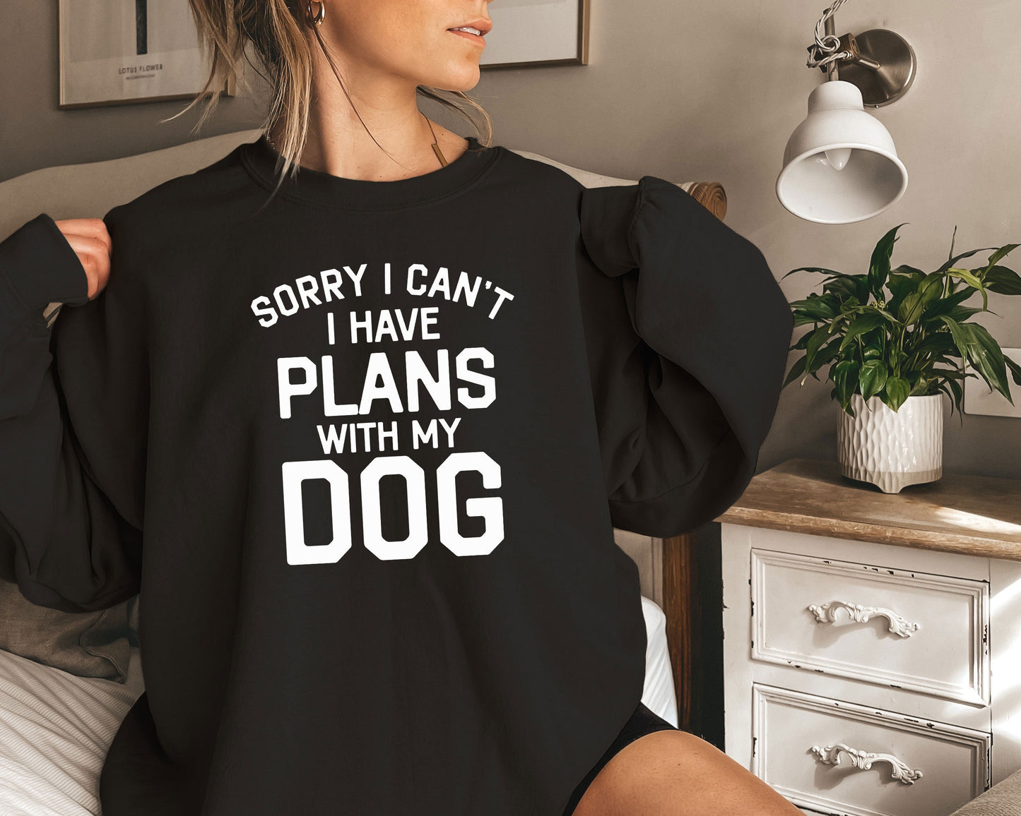 a woman sitting on a bed wearing a black sweatshirt that says sorry i can &#39;