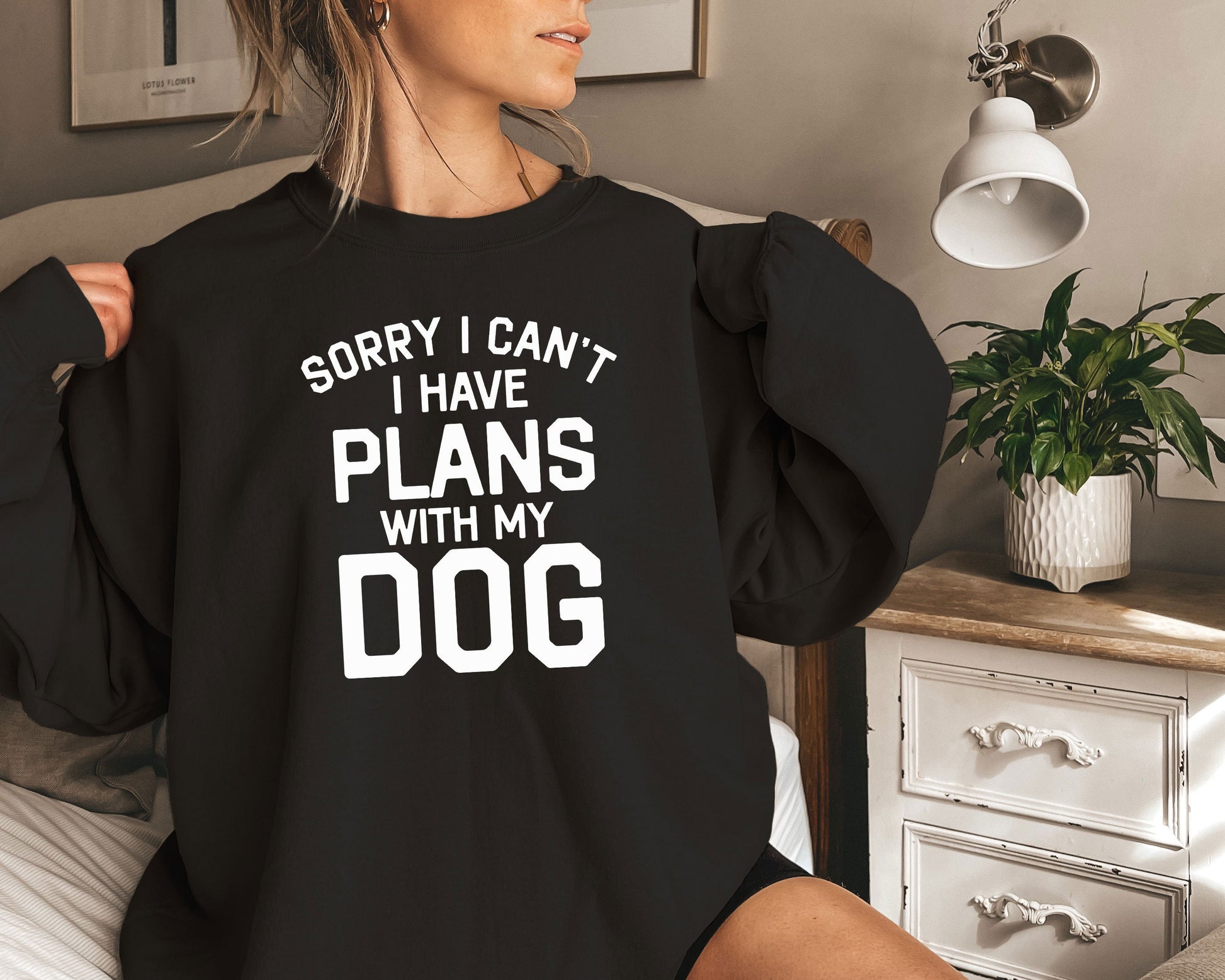 a woman sitting on a bed wearing a black sweatshirt that says sorry i can &#39;