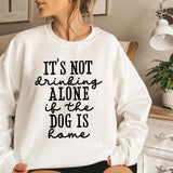 a woman sitting on a bed wearing a sweatshirt that says it's not drinking