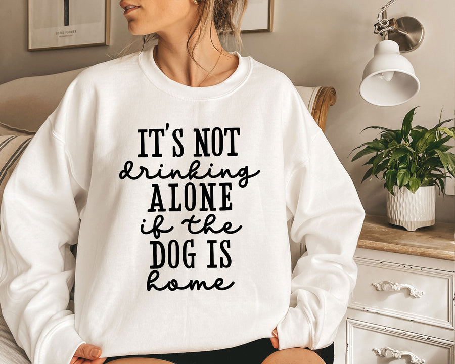 a woman sitting on a bed wearing a sweatshirt that says it's not drinking