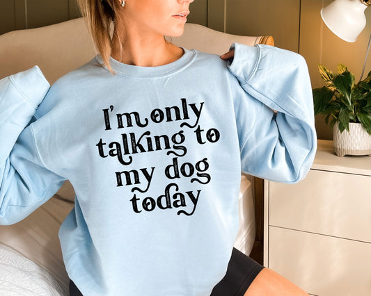 a woman sitting on a bed wearing a blue sweatshirt