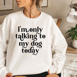 a woman sitting on a bed wearing a sweatshirt that says i'm only talking
