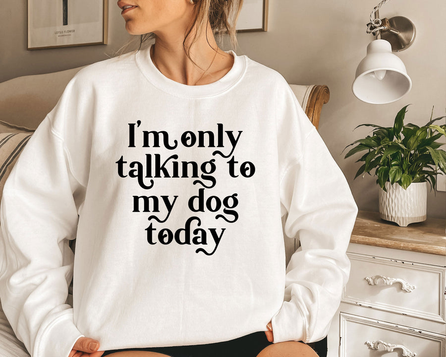 a woman sitting on a bed wearing a sweatshirt that says i'm only talking