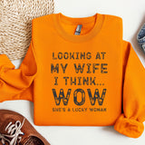 an orange shirt that says looking at my wife i think wow she's a