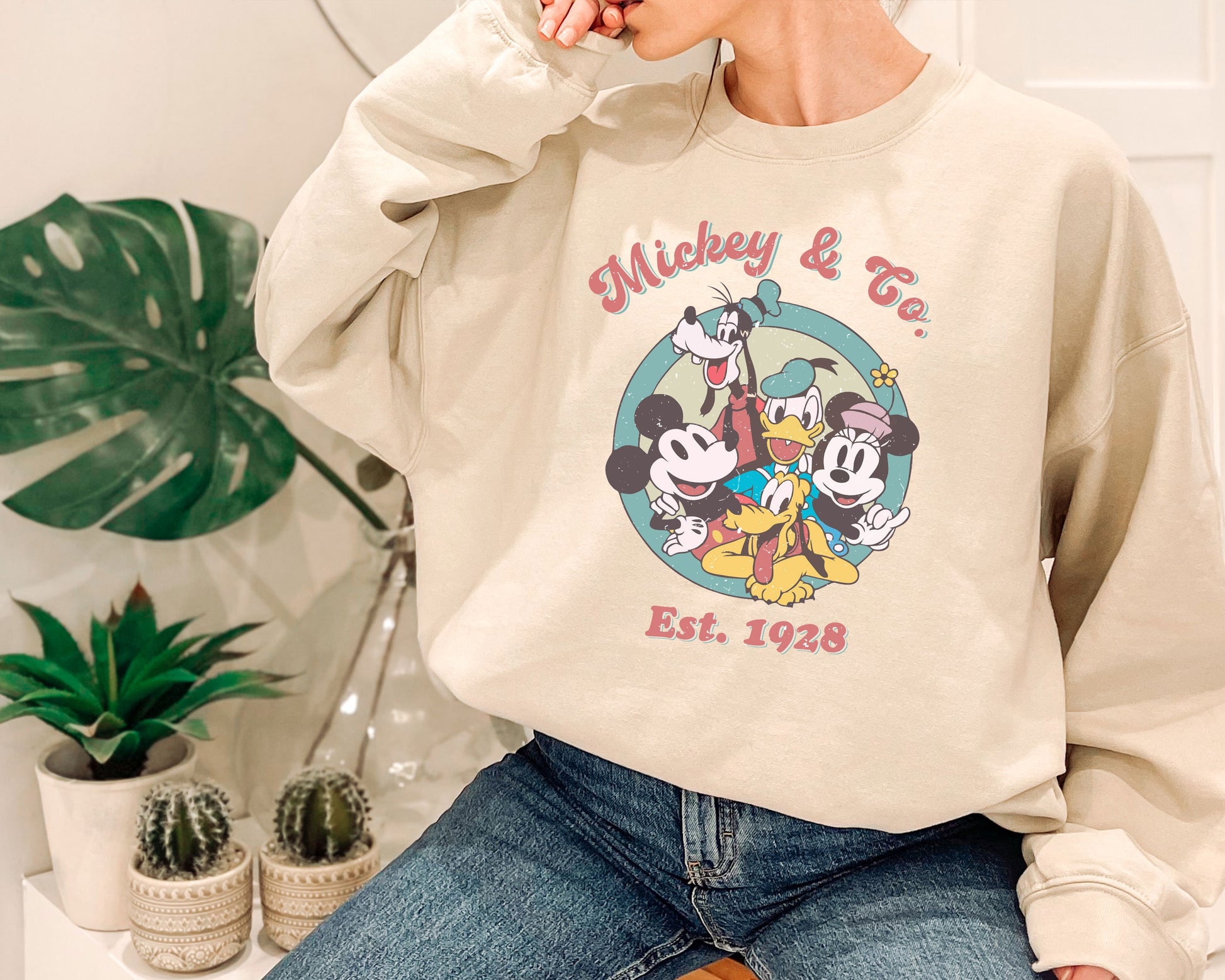 a woman sitting on a chair wearing a mickey mouse sweatshirt