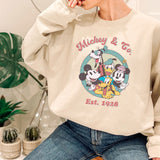 a woman sitting on a chair wearing a mickey mouse sweatshirt