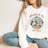 a woman sitting on the floor wearing a mickey mouse sweatshirt