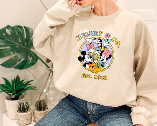 a woman sitting on a chair wearing a mickey mouse sweatshirt