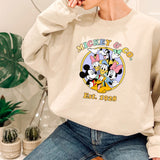 a woman sitting on a chair wearing a mickey mouse sweatshirt