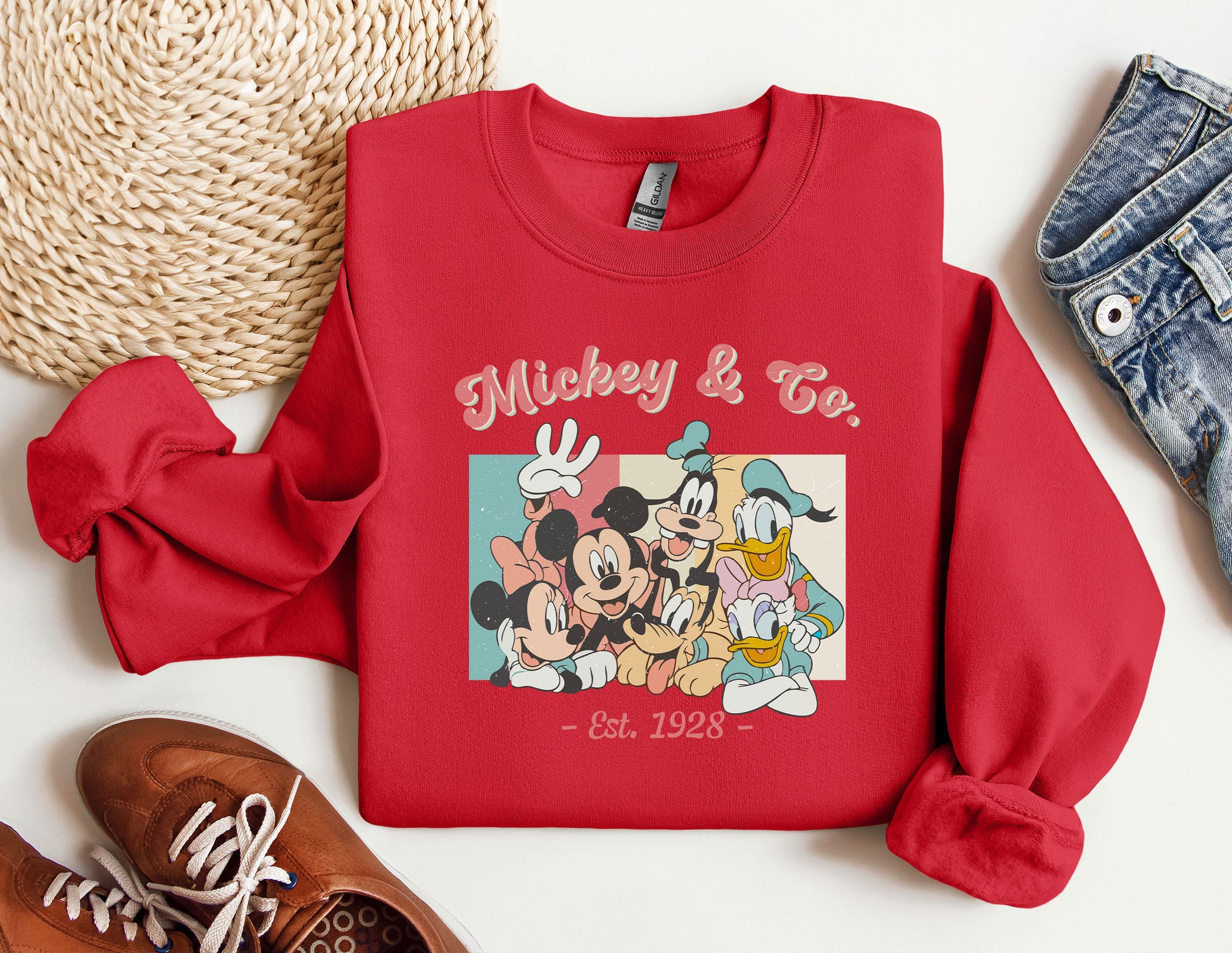 a red mickey and friends sweatshirt next to a pair of sneakers