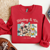 a red mickey and friends sweatshirt next to a pair of sneakers