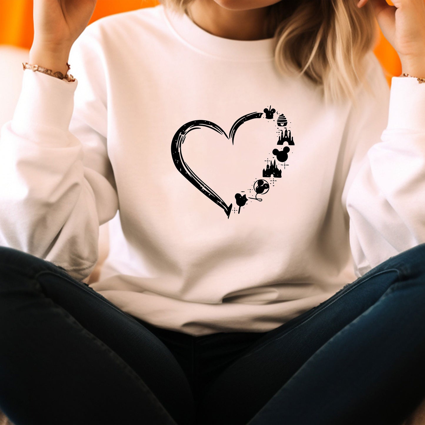 a woman sitting on the floor wearing a white shirt with a heart drawn on it