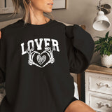 a woman sitting on a bed wearing a black sweatshirt