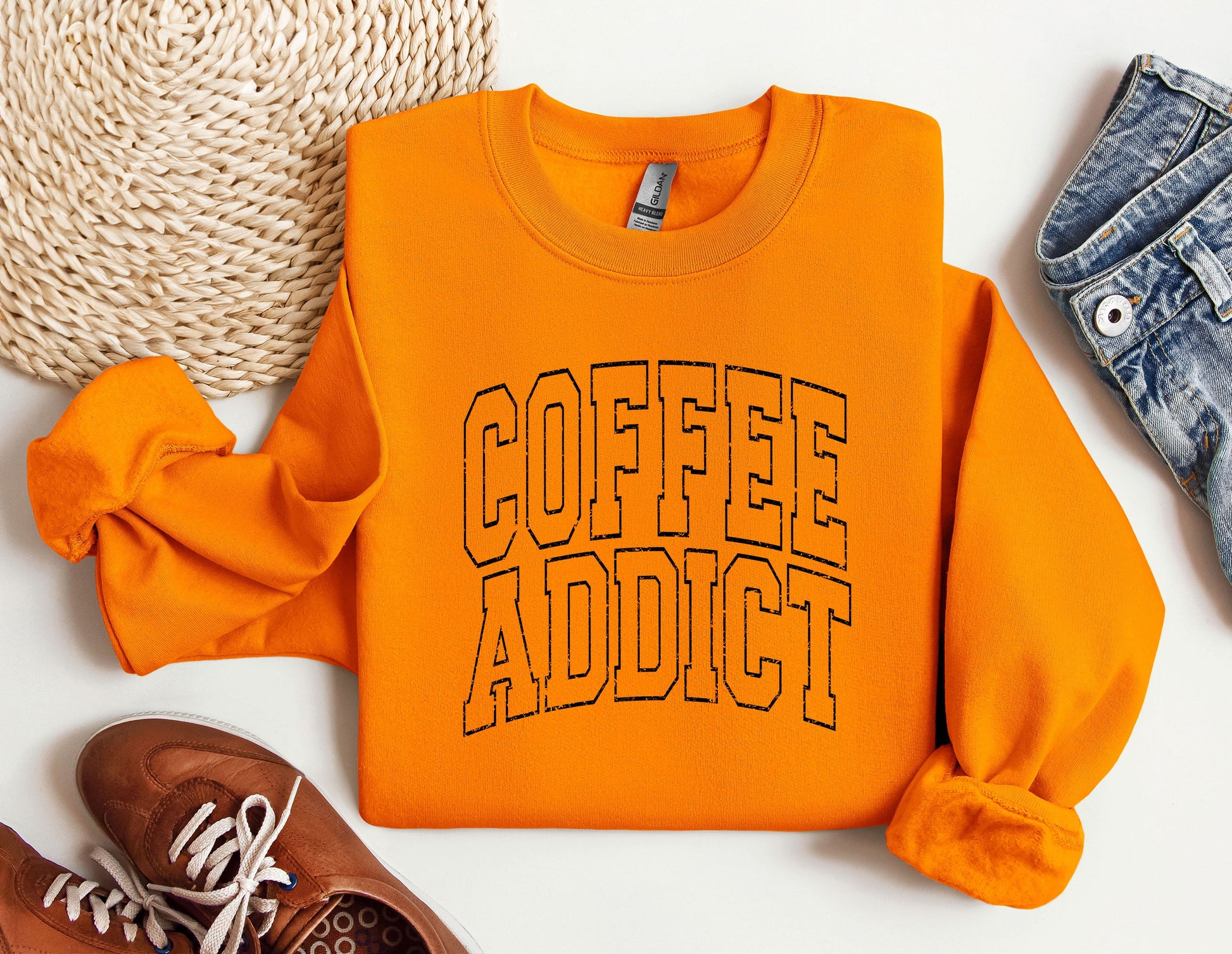 an orange sweatshirt that says coffee addict next to a pair of sneakers