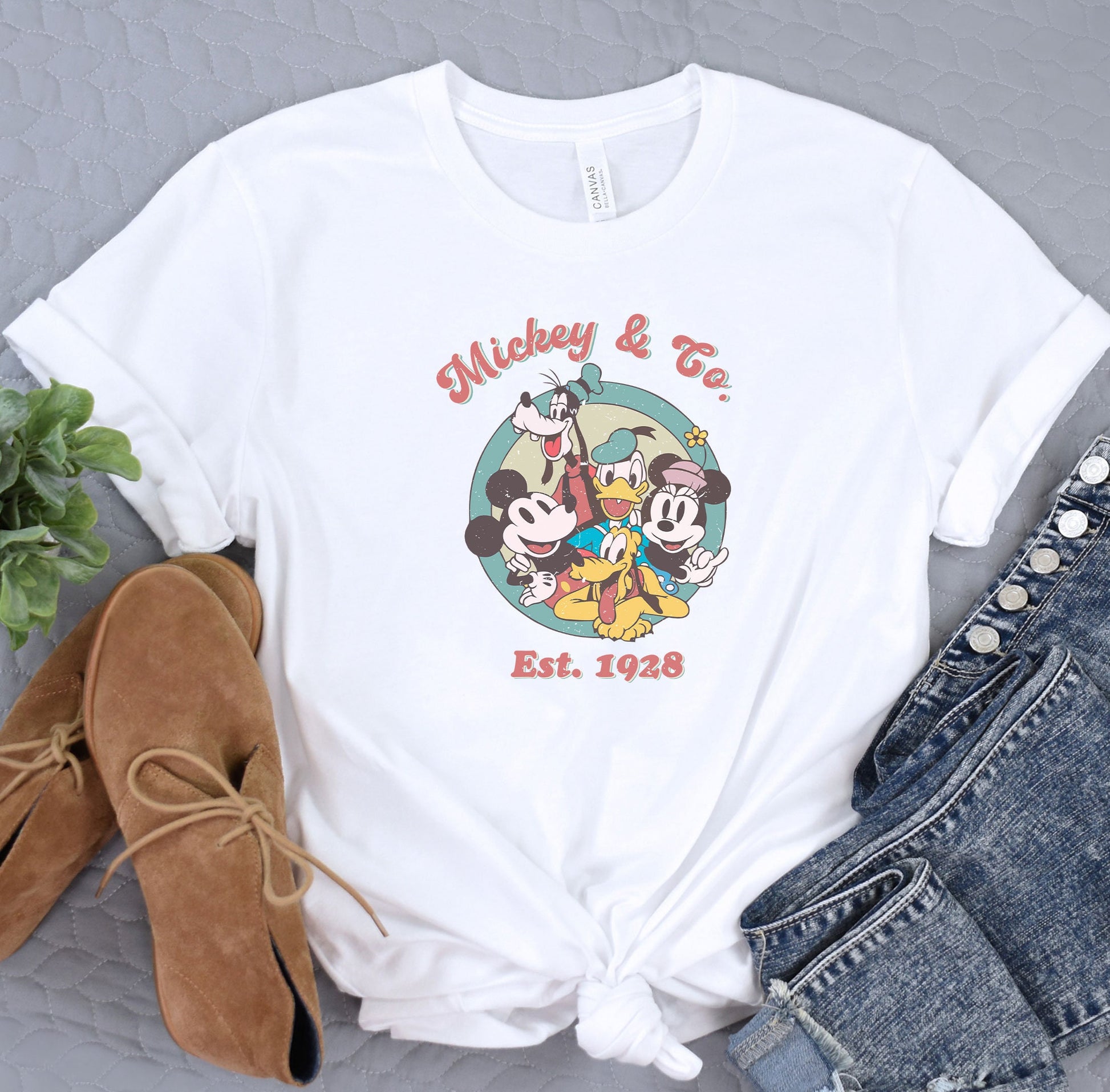 a mickey mouse and friends t - shirt next to a pair of jeans