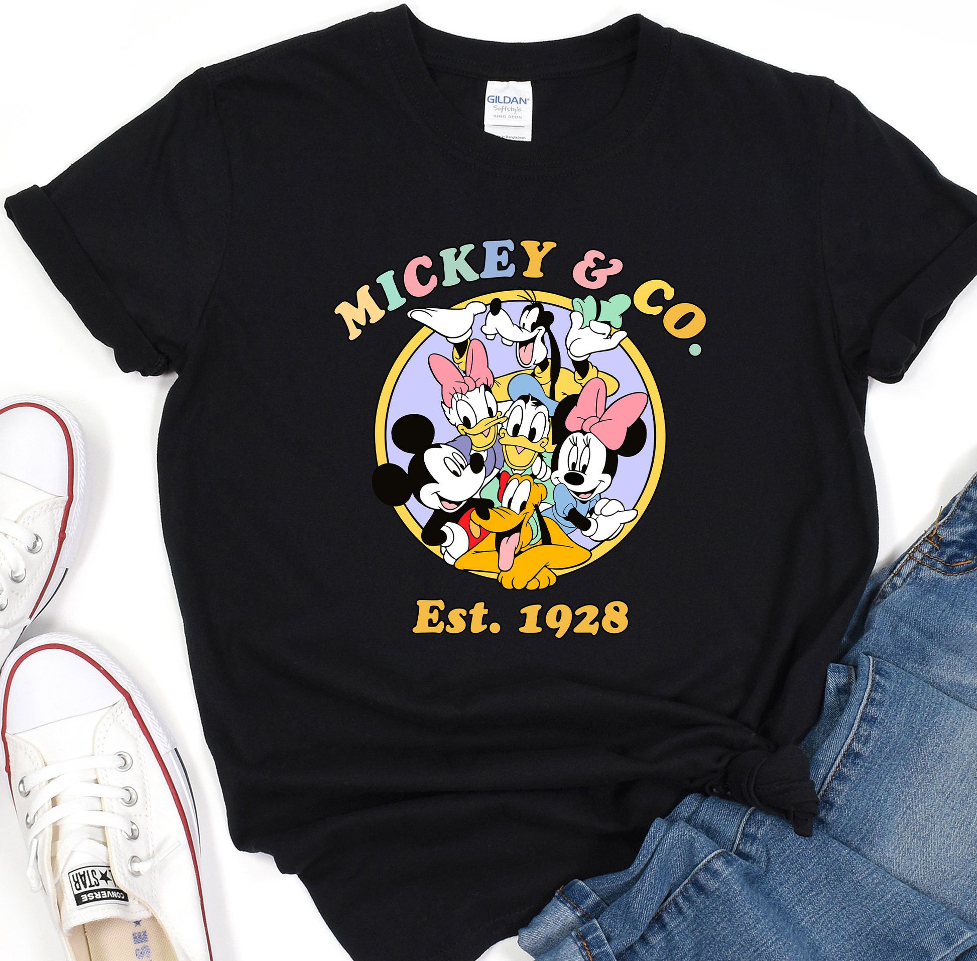 a mickey mouse t - shirt sitting on top of a pair of jeans