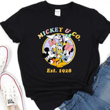 a mickey mouse t - shirt sitting on top of a pair of jeans