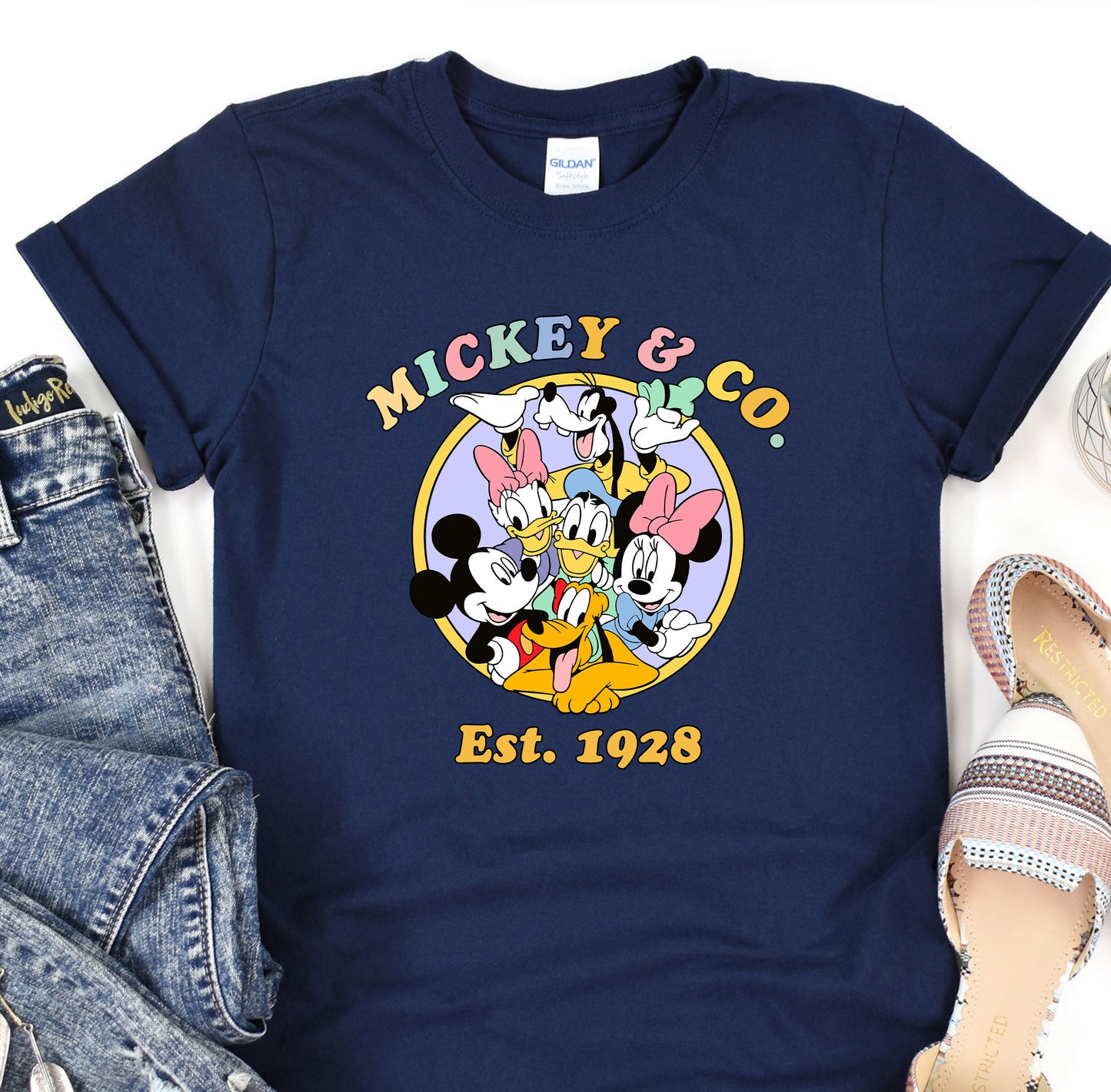 a mickey mouse t - shirt sitting on top of a pair of jeans