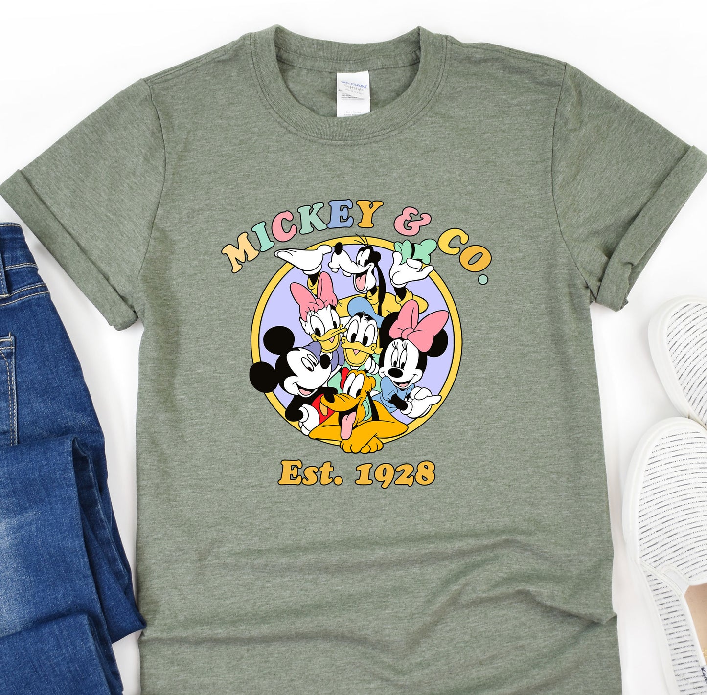 a mickey mouse t - shirt sitting on top of a pair of jeans