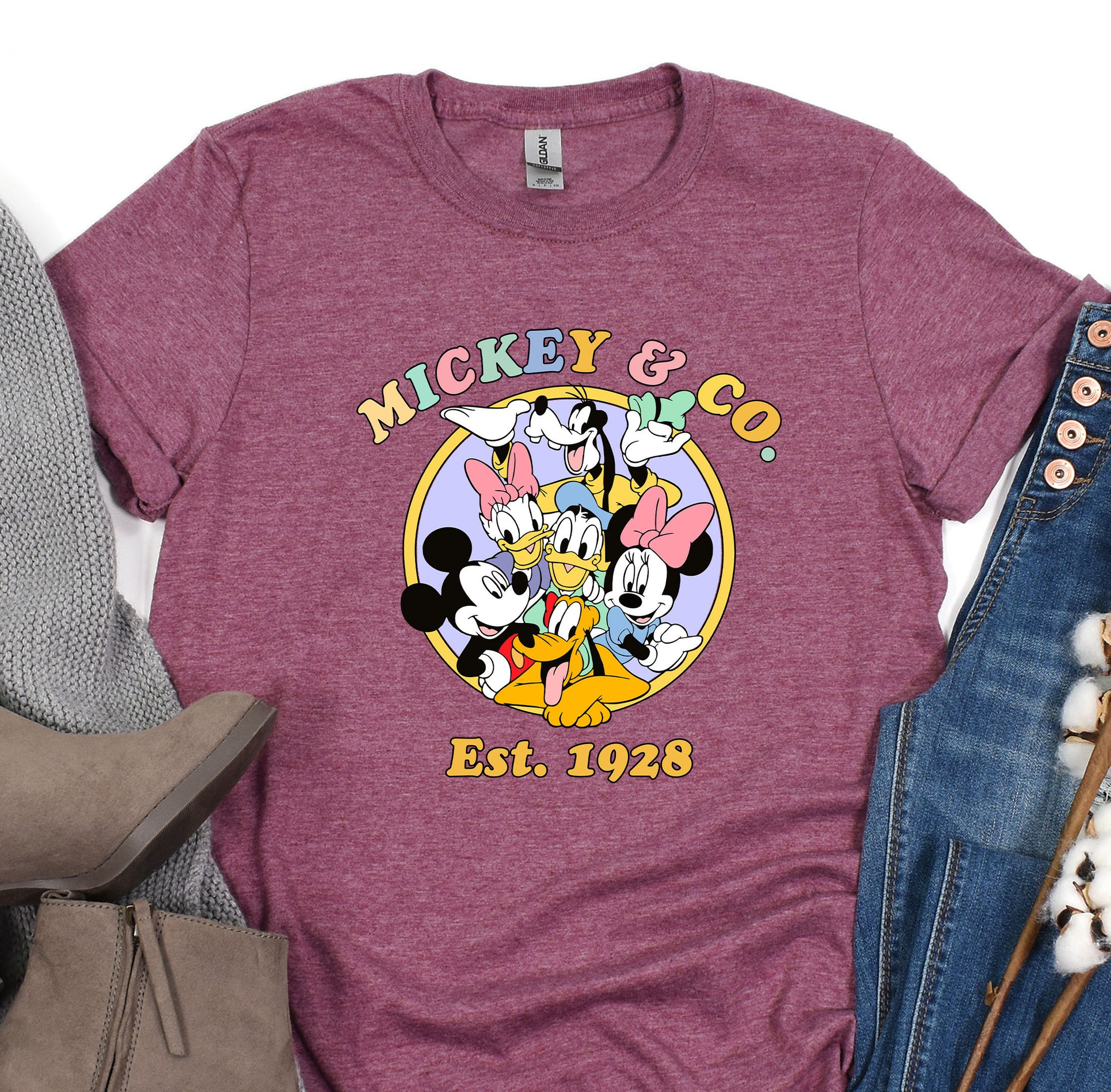 a mickey mouse t - shirt sitting on top of a pair of jeans