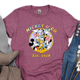 a mickey mouse t - shirt sitting on top of a pair of jeans