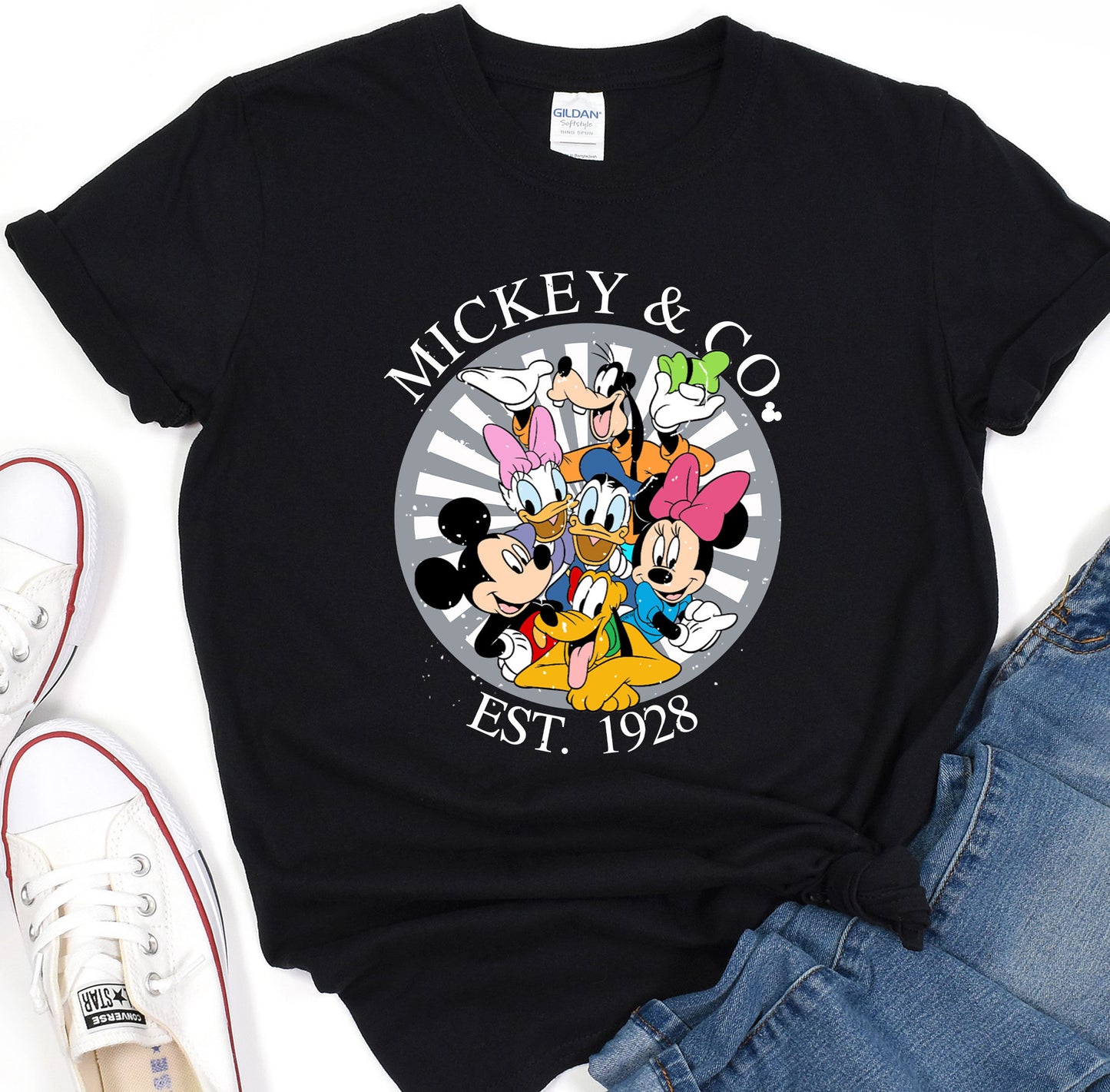 a mickey and mickey mouse t - shirt sitting on top of a pair of jeans