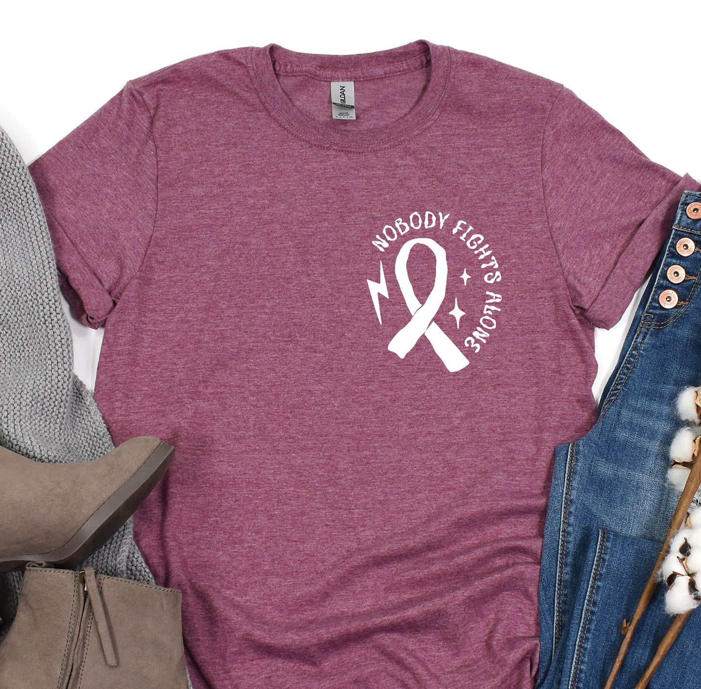 a t - shirt with a pink ribbon on it next to a pair of jeans