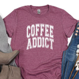 a t - shirt that says coffee addict next to a pair of jeans