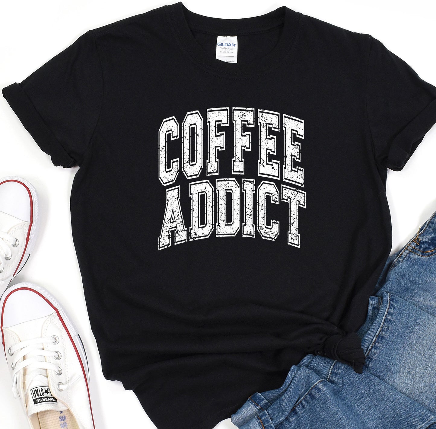 a t - shirt that says coffee addict next to a pair of jeans