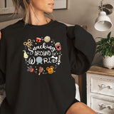 a woman sitting on a bed wearing a black sweatshirt
