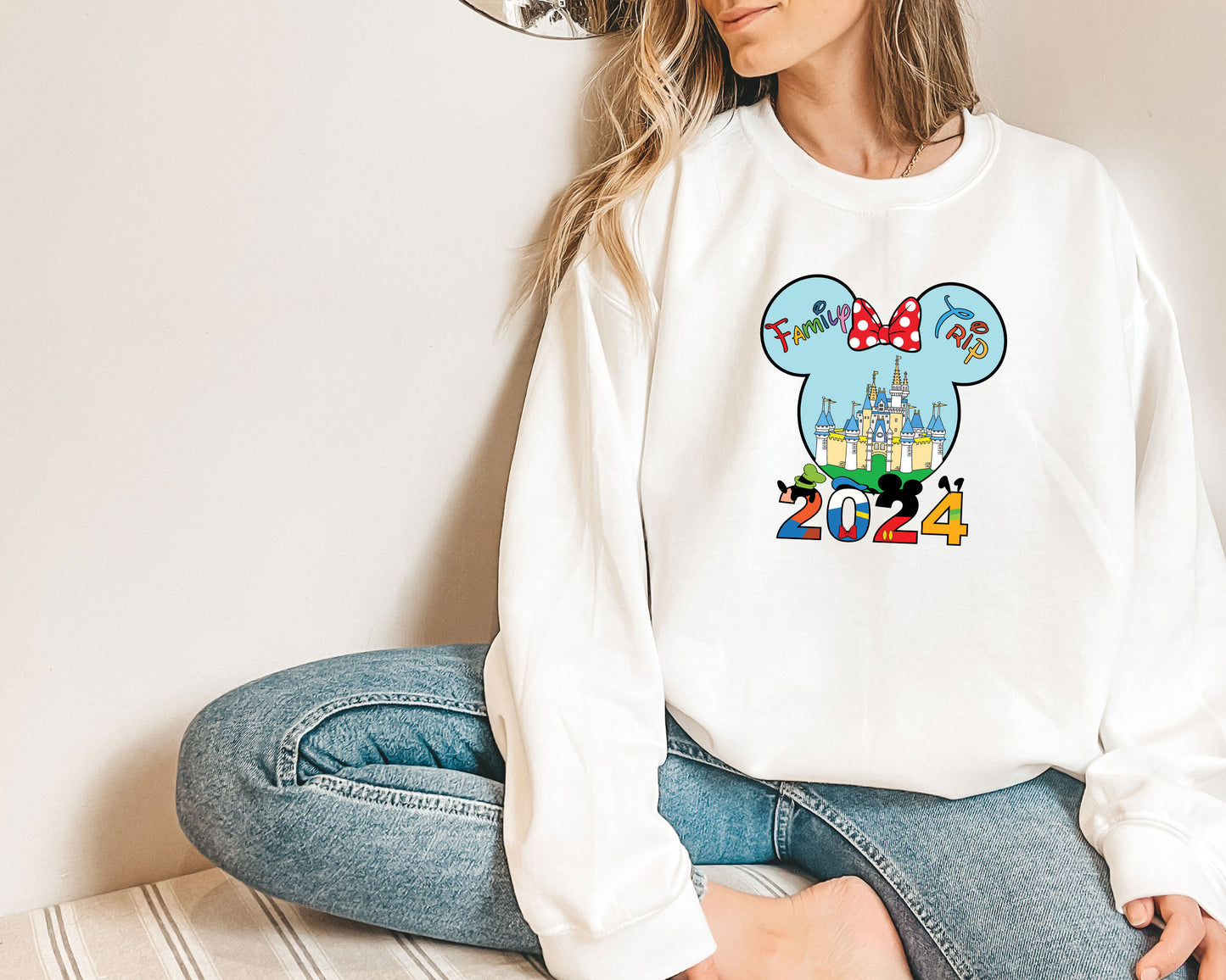 a woman sitting on the floor wearing a mickey mouse shirt