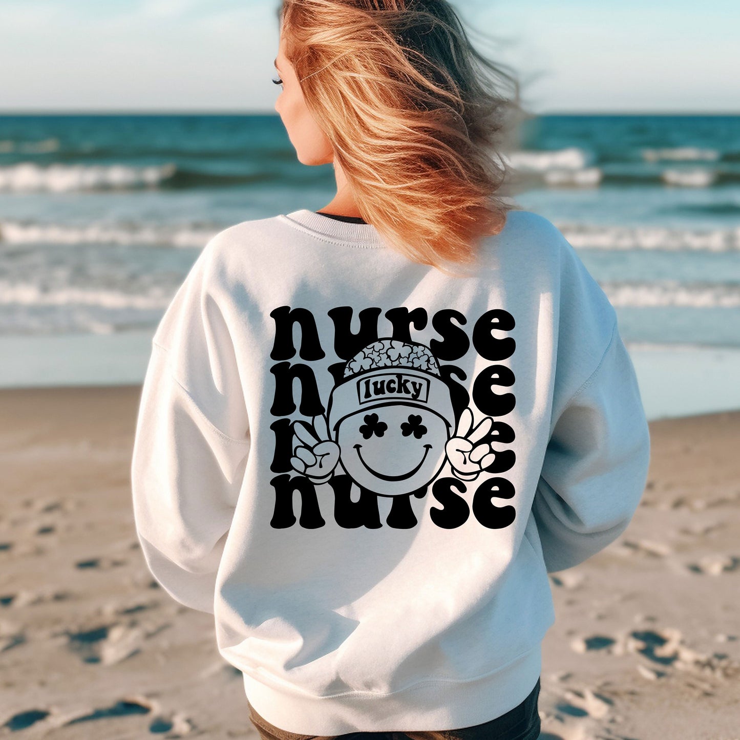 a woman standing on a beach wearing a nurse sweatshirt