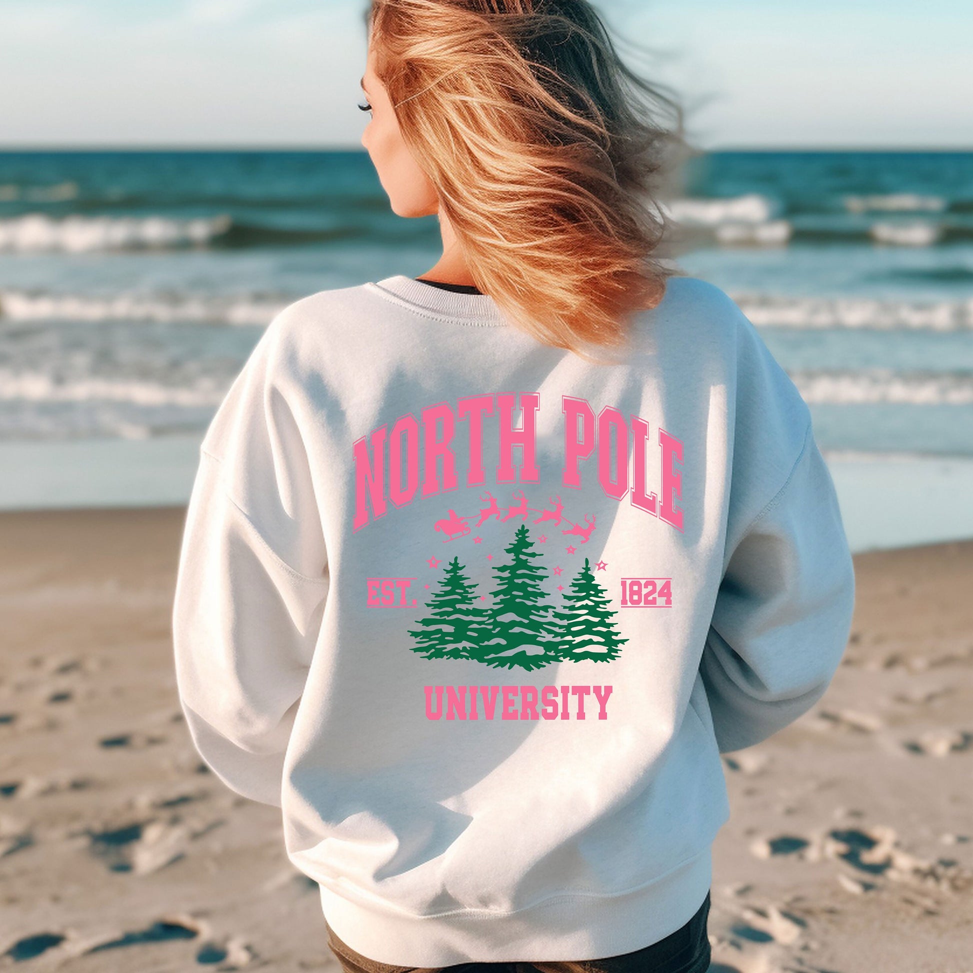 a woman standing on a beach wearing a sweatshirt