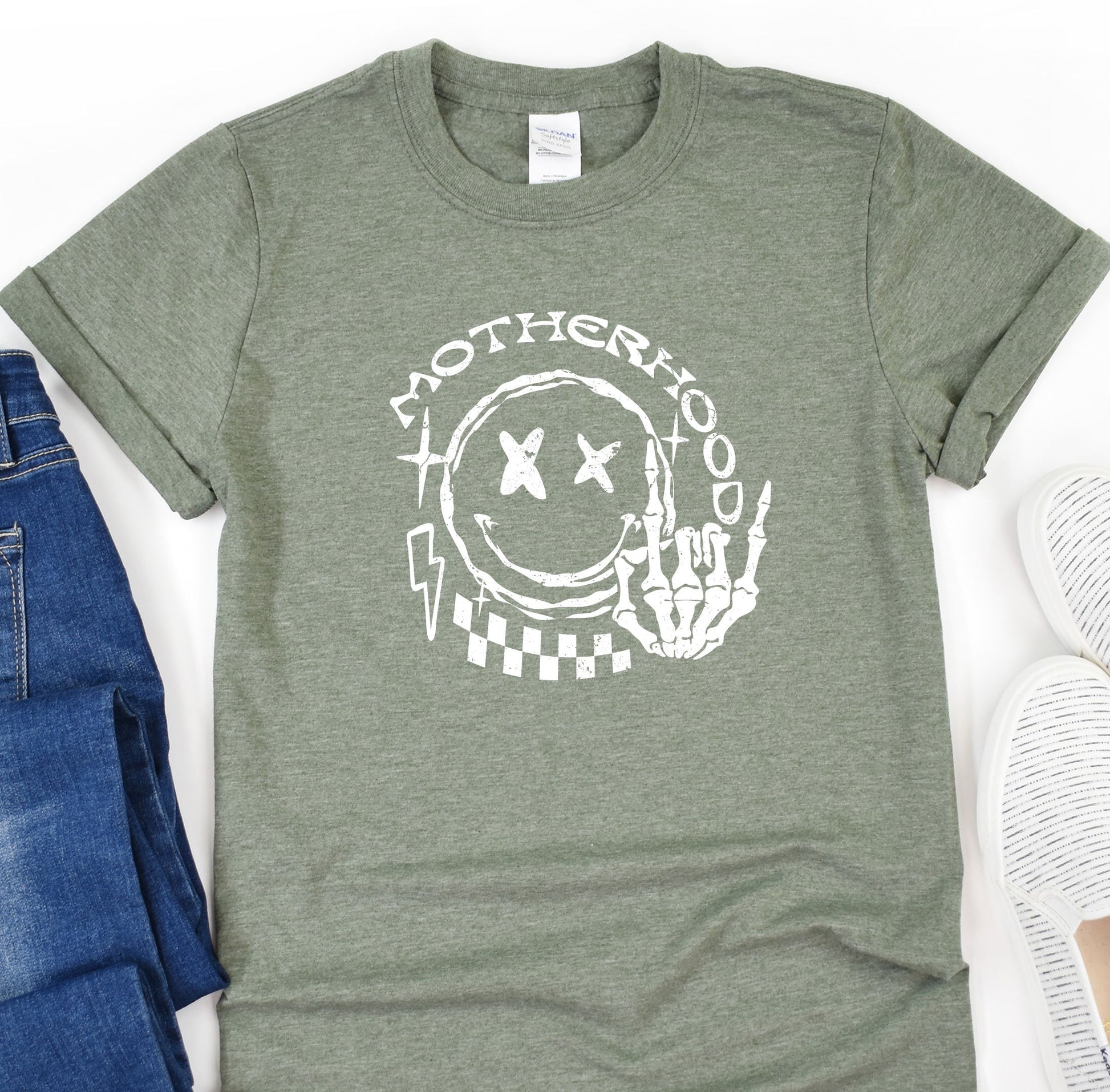 a t - shirt that says motherhood on it next to a pair of jeans