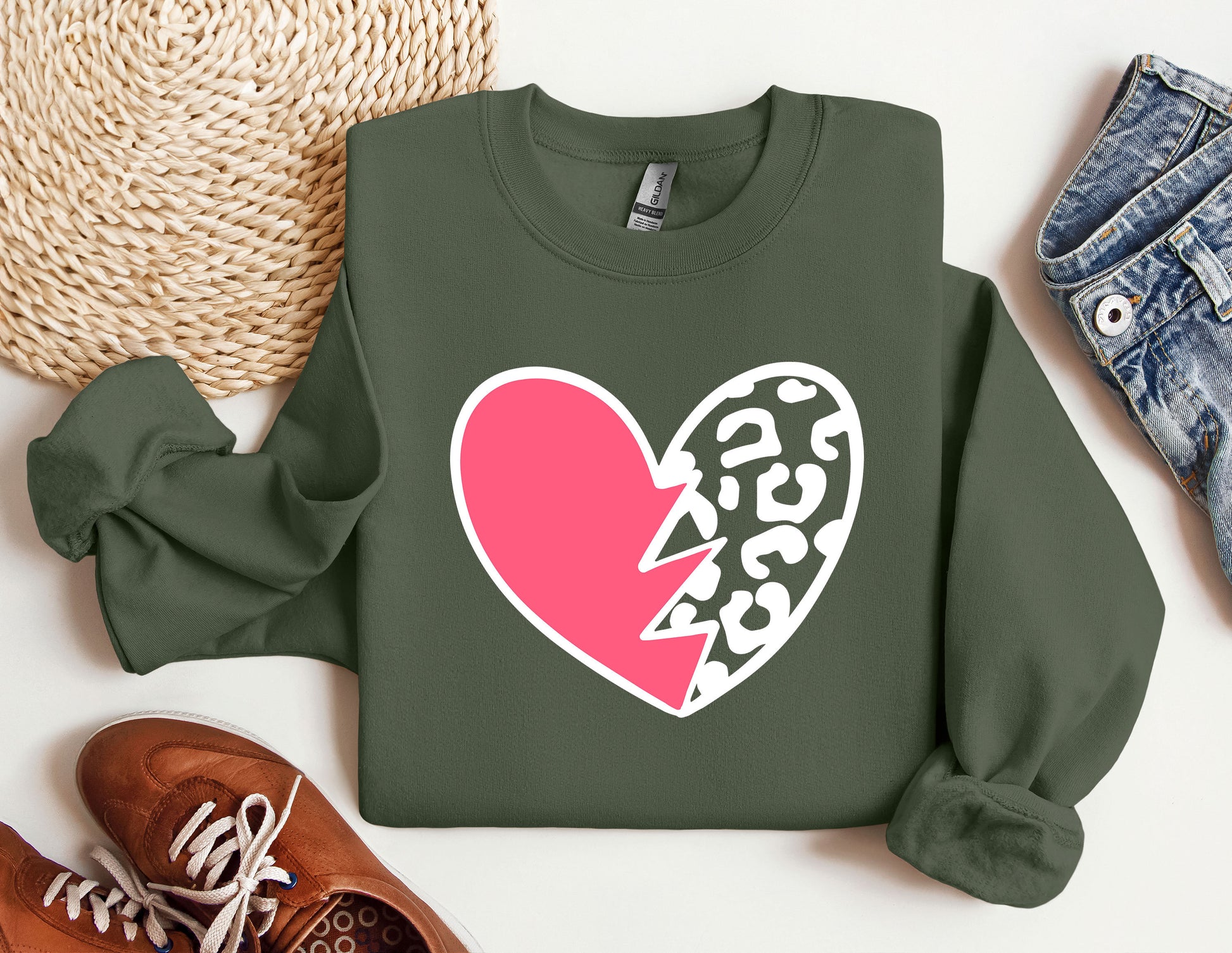 a green sweater with a pink heart and a broken heart