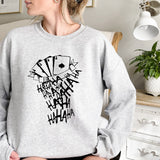 a woman sitting on a bed wearing a sweatshirt with playing cards on it