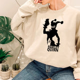 a woman sitting on a stool wearing a sweatshirt with a picture of a clown on