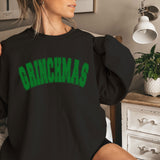 a woman sitting on a bed wearing a black sweatshirt with green lettering